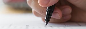 Hand mit Stift schreibt auf Papier